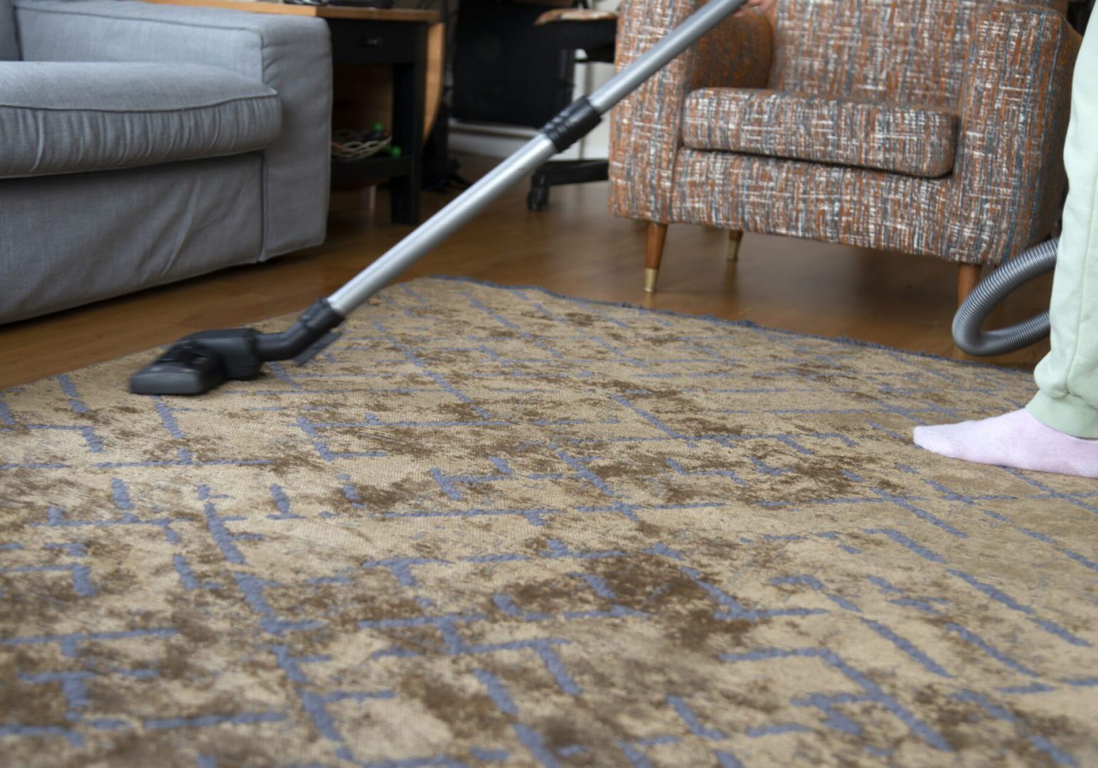 Woman vacuuming house Vacuuming a patterned rug in living room.