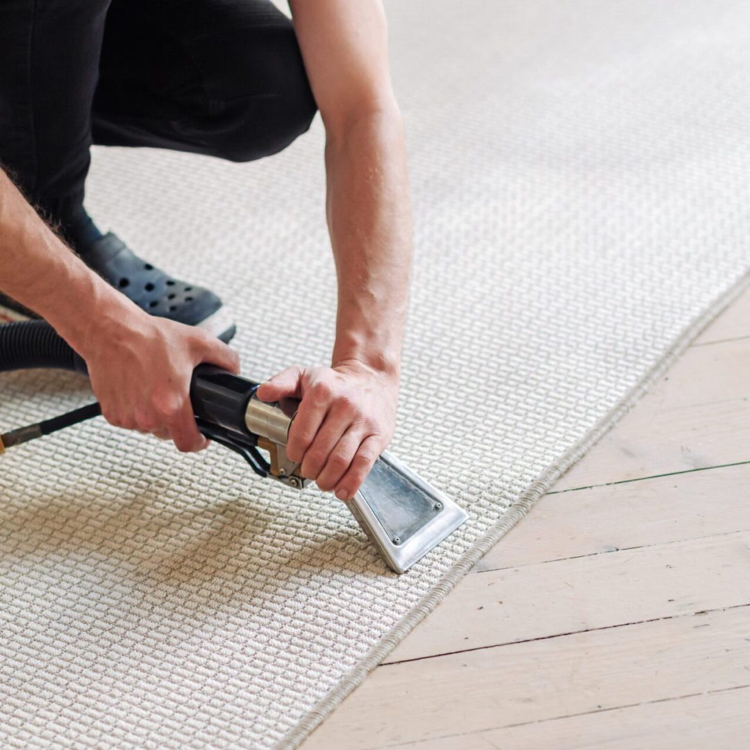 Close-up of housekeeper holding modern washing vacuum cleaner and cleaning dirty carpet with stain with professionally detergent. Professional spring clean at home concept Person cleaning carpet with vacuum tool.