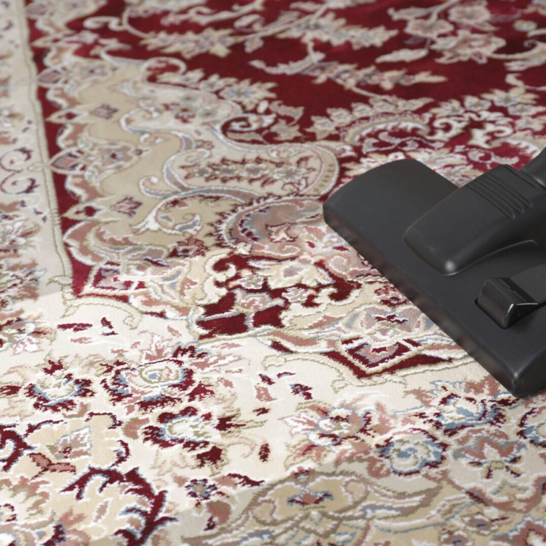 Hoovering carpet with vacuum cleaner, space for text. Clean trace on dirty surface Vacuum cleaner on patterned red and beige carpet.