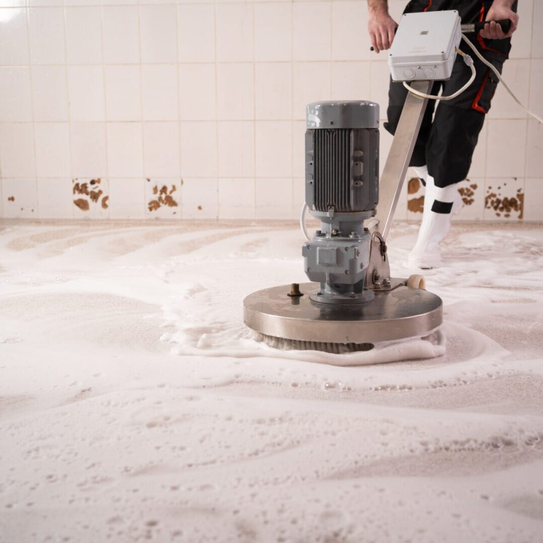 Worker washing long carpet chemical cleaning with professionally disk machine, close-up. Regular clean-up Floor cleaning machine in action with foam.
